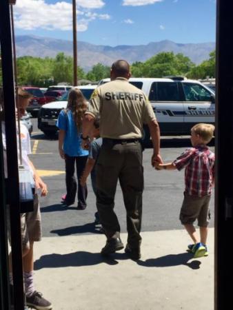 Photo showing a police officer holding hands with a kid after shopping